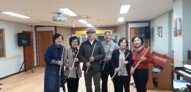 넓은 실내에서 플루트를 든 여섯 사람이 나란히 선 모습